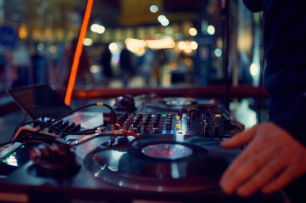 turntable, hand of dj on the vinyl record at night club. blured background